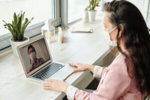 A woman is actively participating in a telehealth session with her healthcare provider.